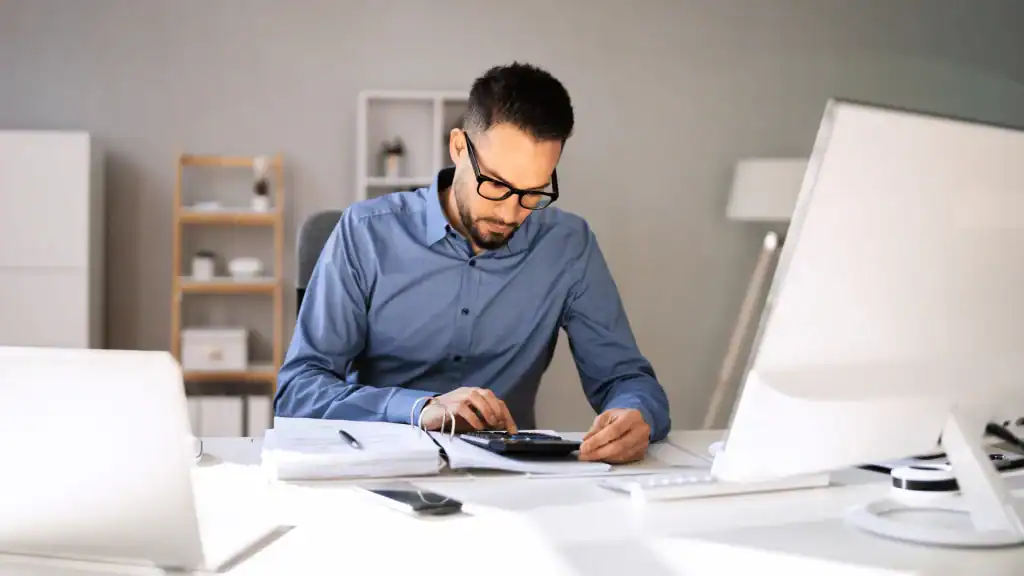 Tax resolution specialist working with documents and calculator for IRS tax settlement.