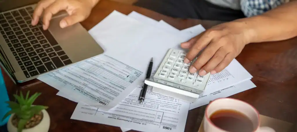 Tax resolution paperwork with calculator and laptop for IRS and tax debt help.